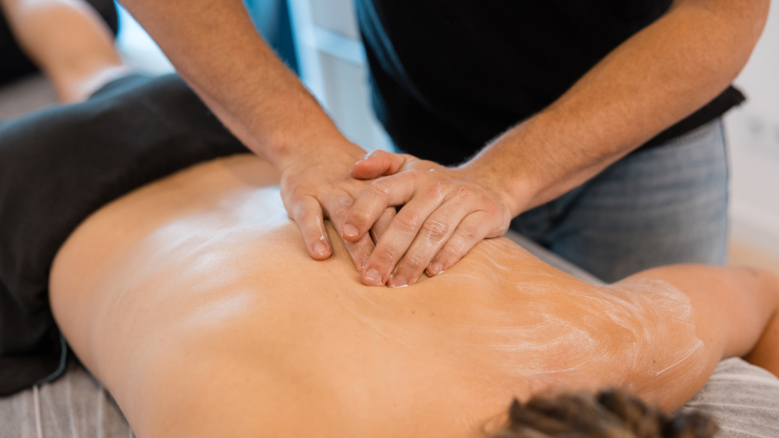 Therapist applying pain relief cream during back massage