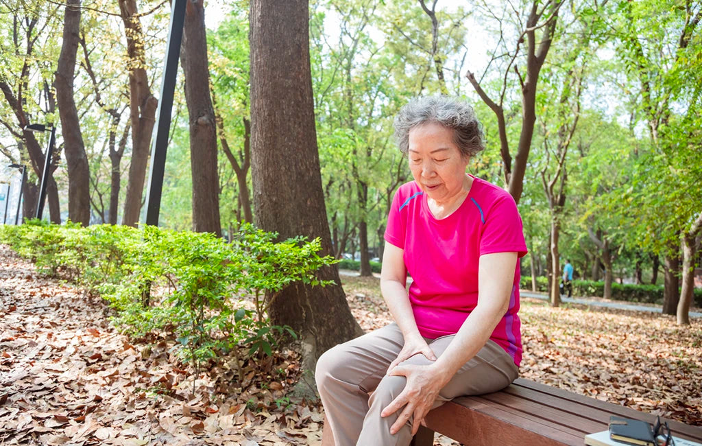 Elderly woman with knee pain sitting in park
