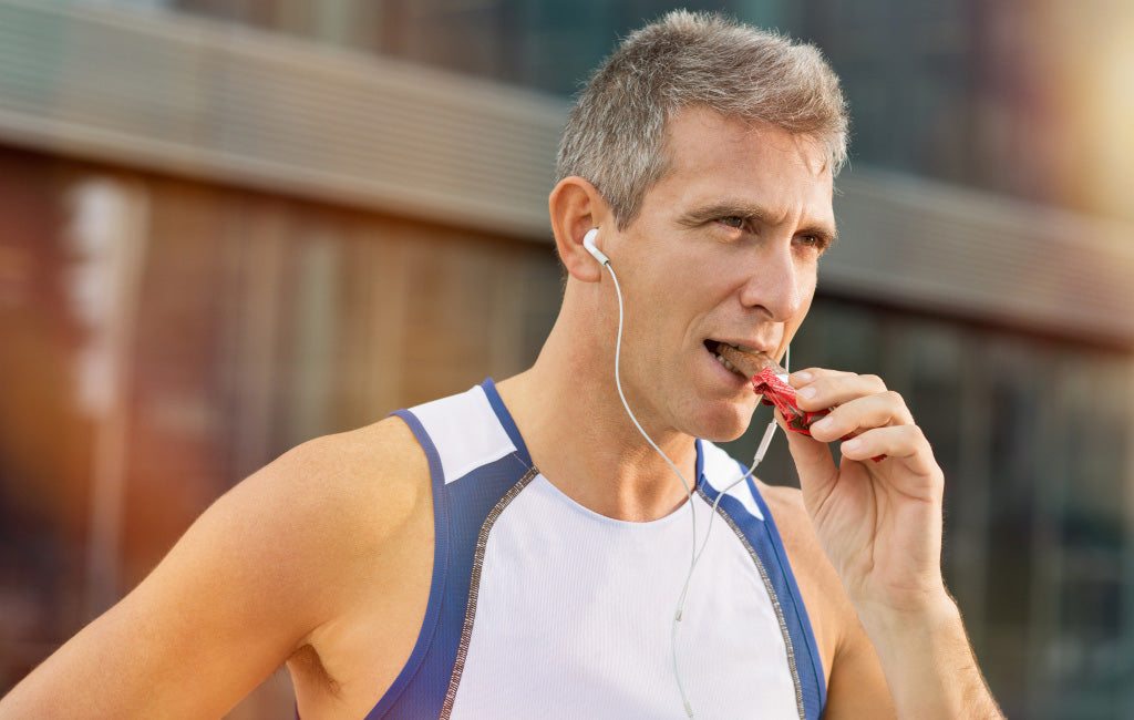 male runner eating chocolate energy bar
