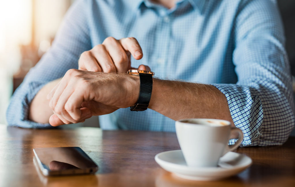man drinking coffee checking watch