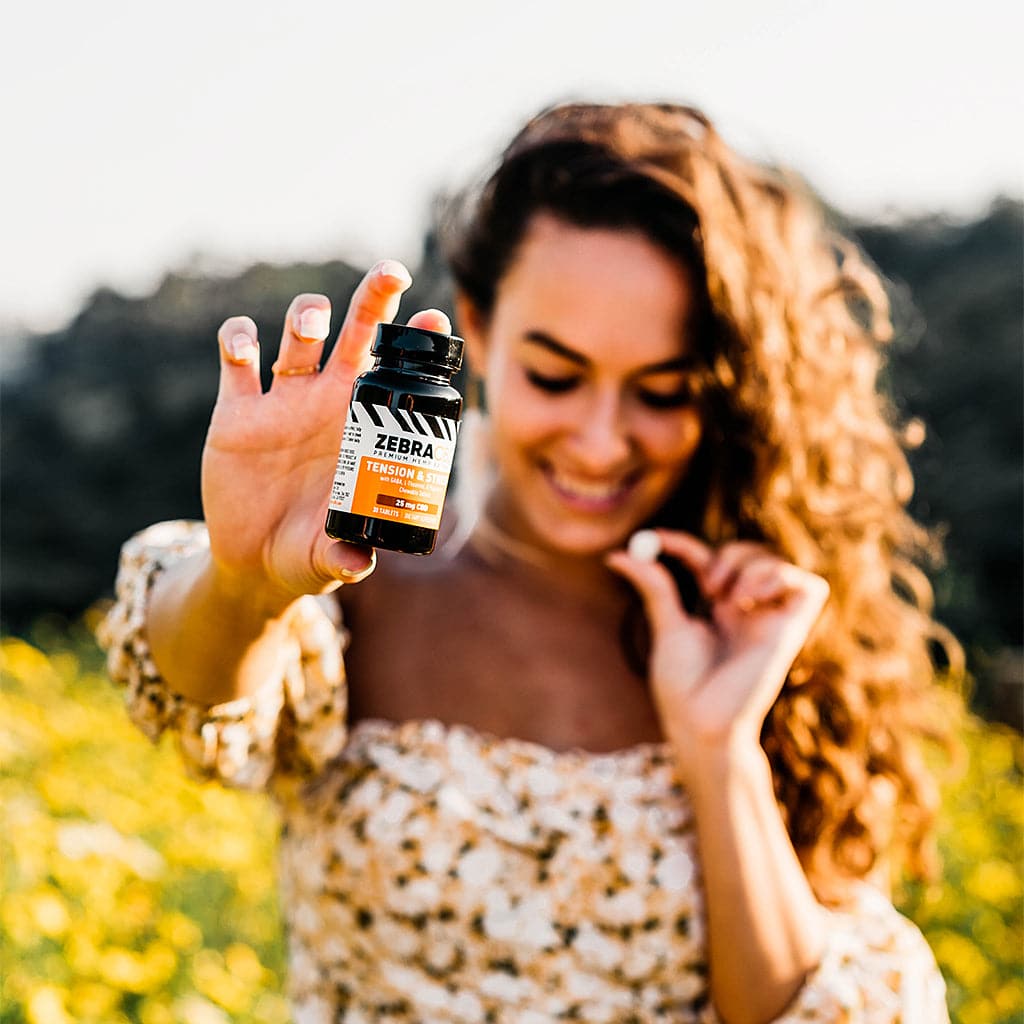 woman holding bottle of cbd tension and stress tablets