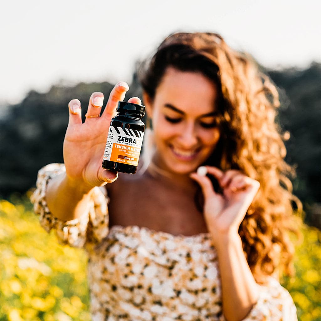  woman holding bottle of cbd tension and stress tablets